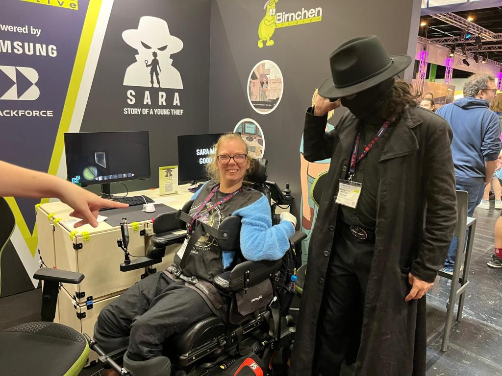 Das Bild zeigt Marlene am Birnchen Stand auf der Gamescom, wo das Spiel SARA - Geschichte einer jungen Diebin präsentiert wird,  mit einem Cosplayer